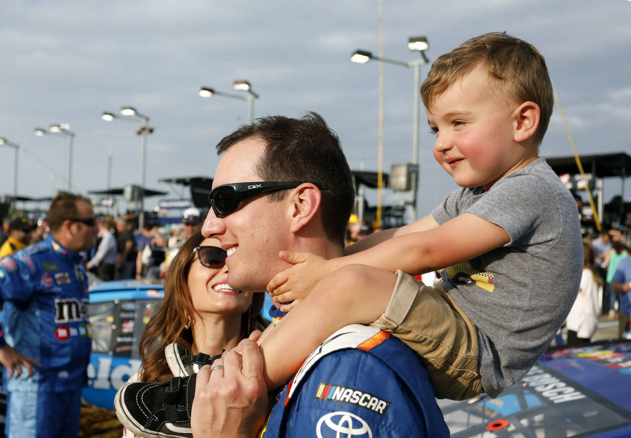FILE - Kyle Busch carries his 2-year-old son, Brexton, as his wife, Samantha, left, watches before ...