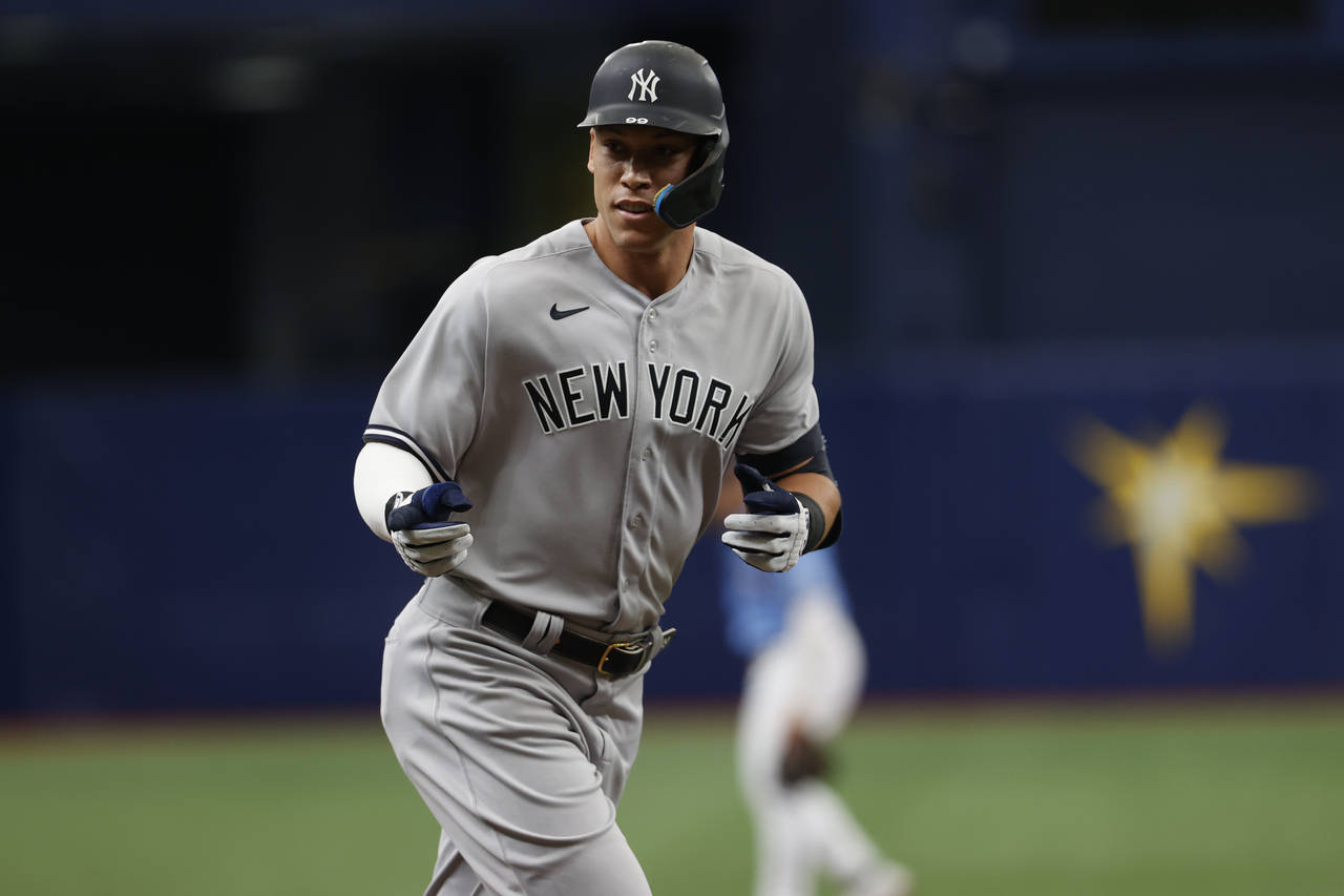 New York Yankees' Aaron Judge point to the dugout while circling the bases after hitting a home run...