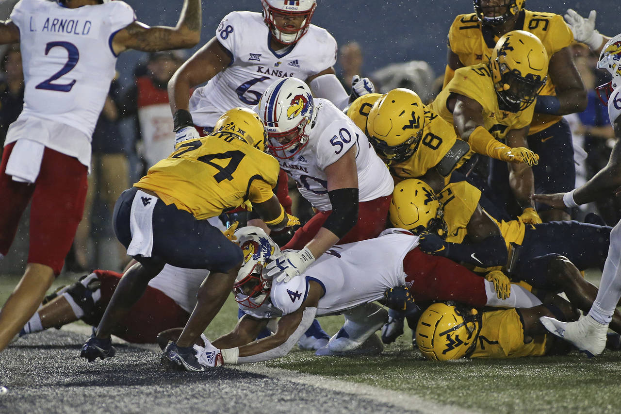 Kansas running back Devin Neal (4) scores a touchdown while defended by West Virginia safety Marcis...