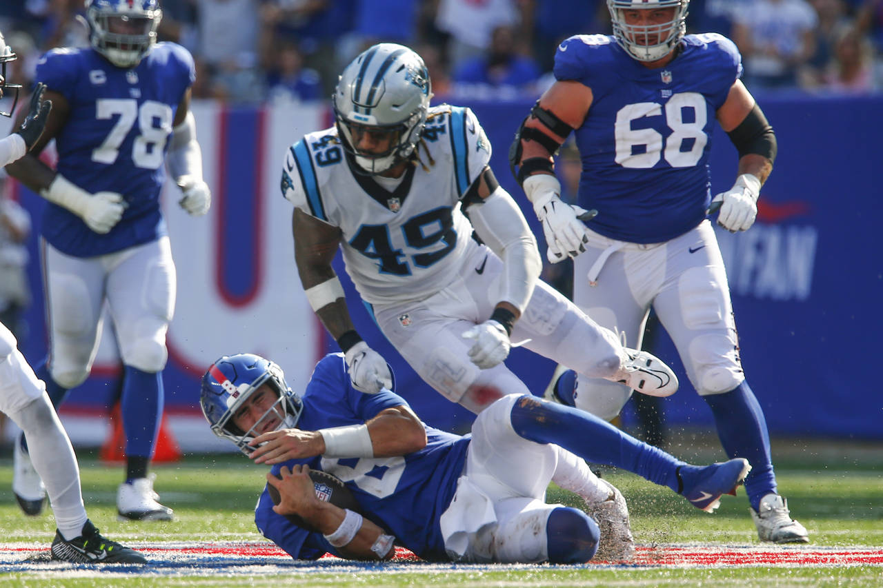 New York Giants quarterback Daniel Jones, bottom, slides after running for a first down during the ...