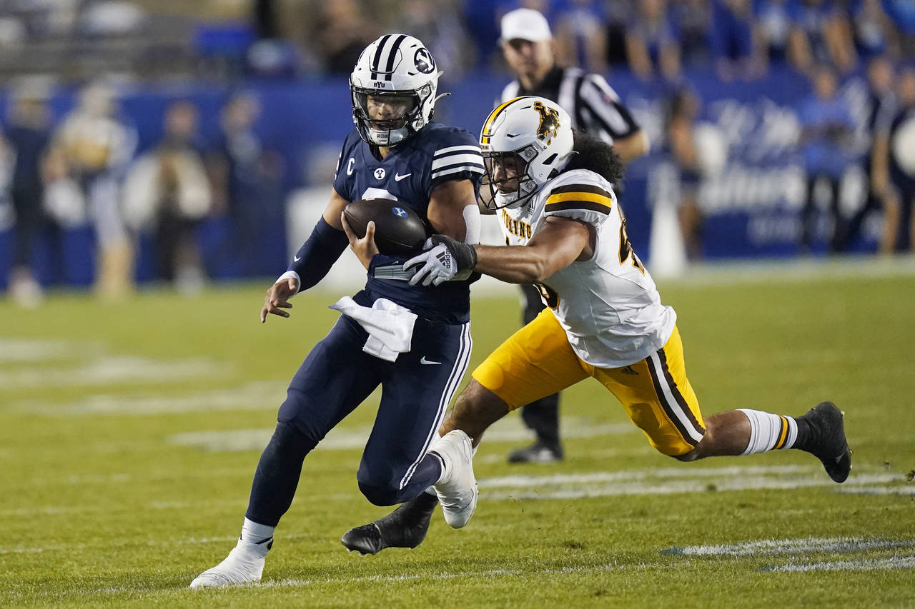 BYU quarterback Jaren Hall carries the ball past Wyoming linebacker Shae Suiaunoa during the first ...