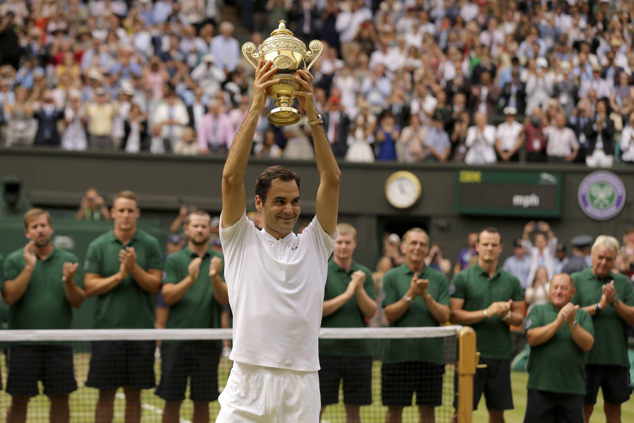 FILE - Switzerland's Roger Federer is applauded by ground staff as he holds the trophy after defeat...