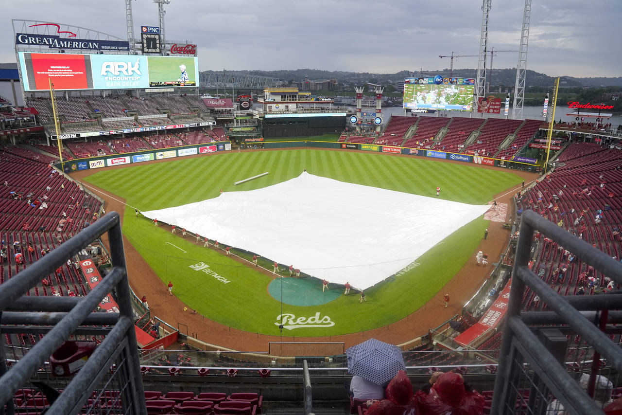 Grounds crew members lay a tarp over the infield prior to a baseball game between the Colorado Rock...