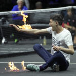 
              A man sets fire on his hand during protest at a match Team World's Diego Schwartzman against Team Europe's Stefanos Tsitsipas on day one of the Laver Cup tennis tournament at the O2 in London, Friday, Sept. 23, 2022. (AP Photo/Kin Cheung)
            