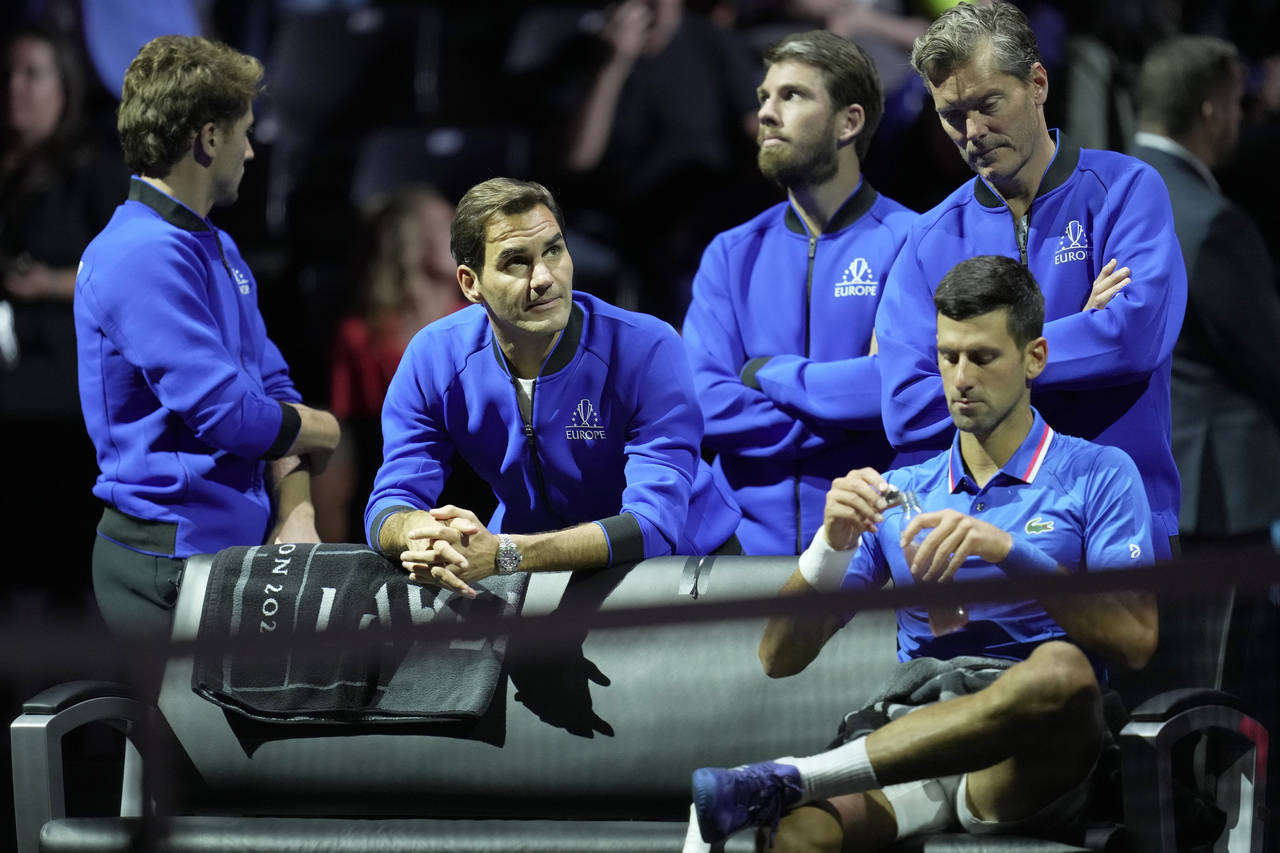 Team Europe's Roger Federer, second left looks up as he stands behind teammate Team Europe's Novak ...