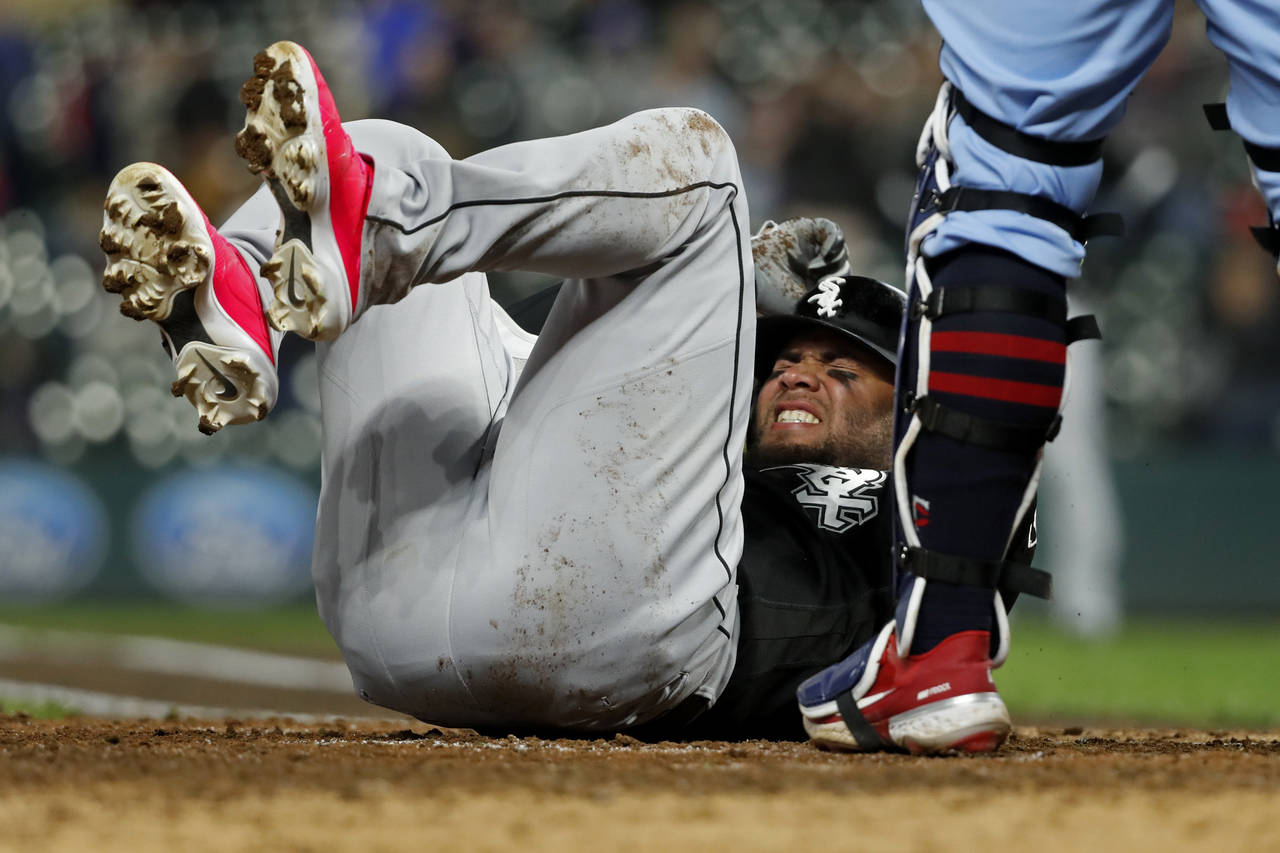 Chicago White Sox' Yoan Moncada reacts after fouling a pitch into his ankle against the Minnesota T...