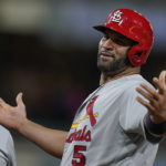 
              St. Louis Cardinals' Albert Pujols jokes with players in the San Diego Padres' dugout as he stands on first base after hitting a single during the ninth inning of a baseball game Tuesday, Sept. 20, 2022, in San Diego. (AP Photo/Gregory Bull)
            