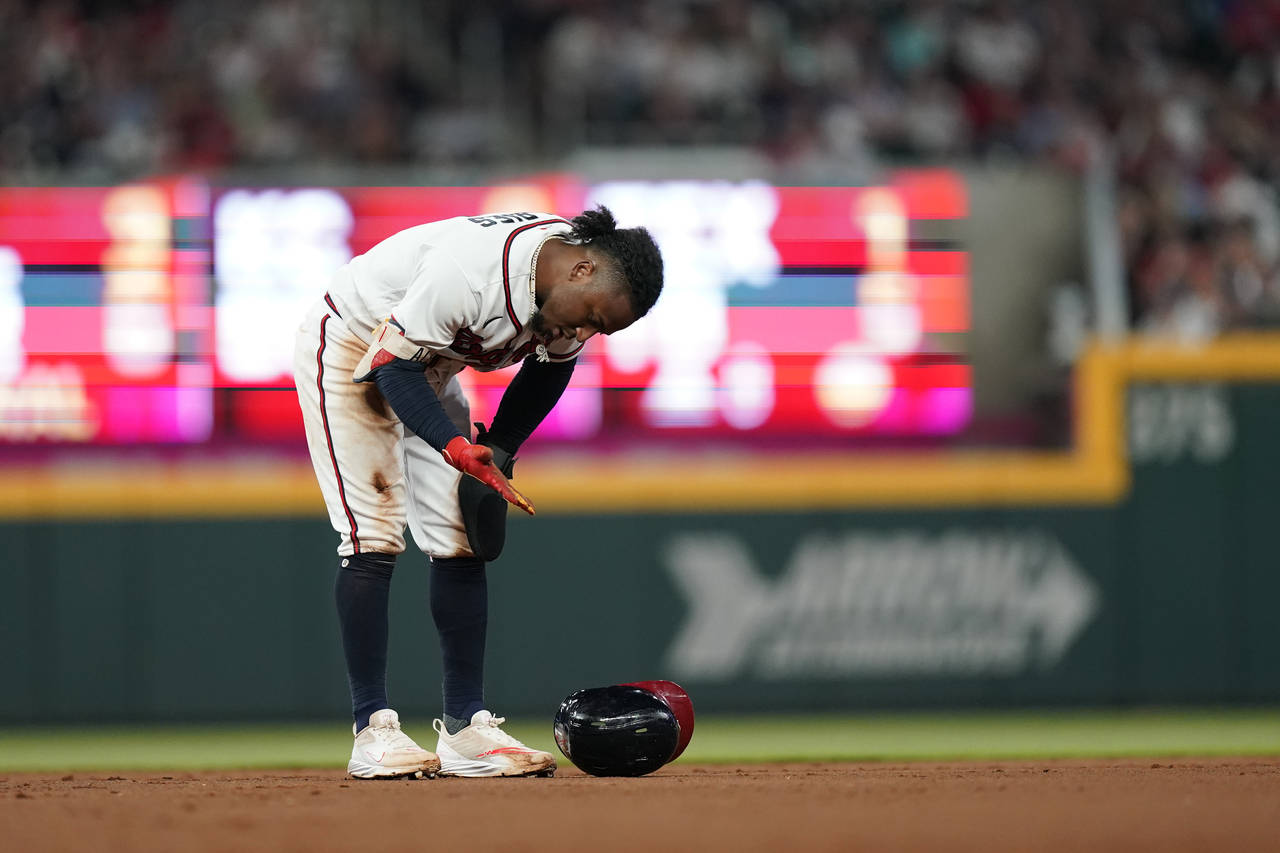 Atlanta Braves' Ozzie Albies looks at his hand after he slid in safely against Philadelphia Phillie...