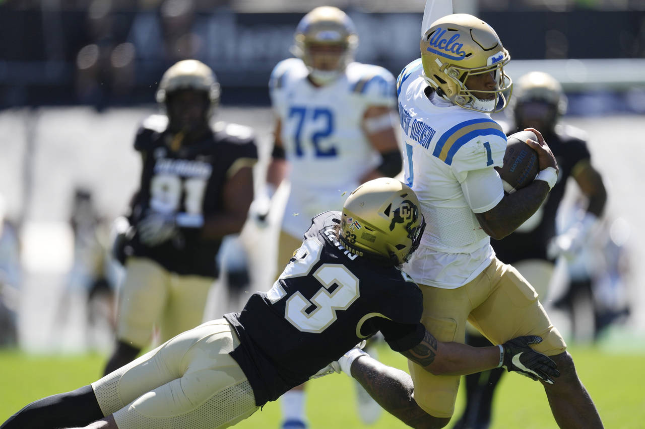 Colorado safety Isaiah Lewis, left, tackles UCLA quarterback Dorian Thompson-Robinson after a long ...