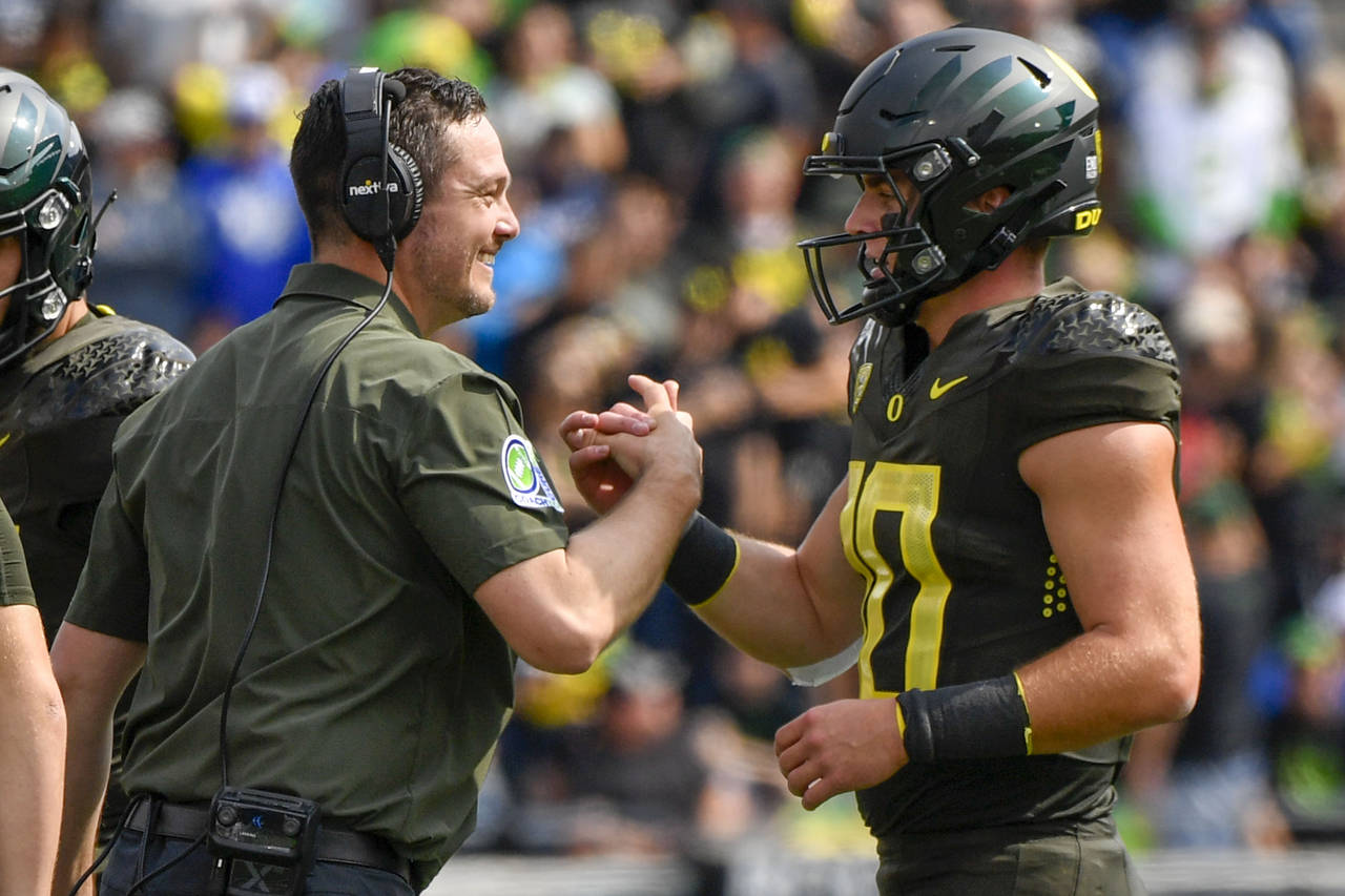 Oregon head coach Dan Lanning greets Oregon quarterback Bo Nix (10) after a touchdown against BYU d...