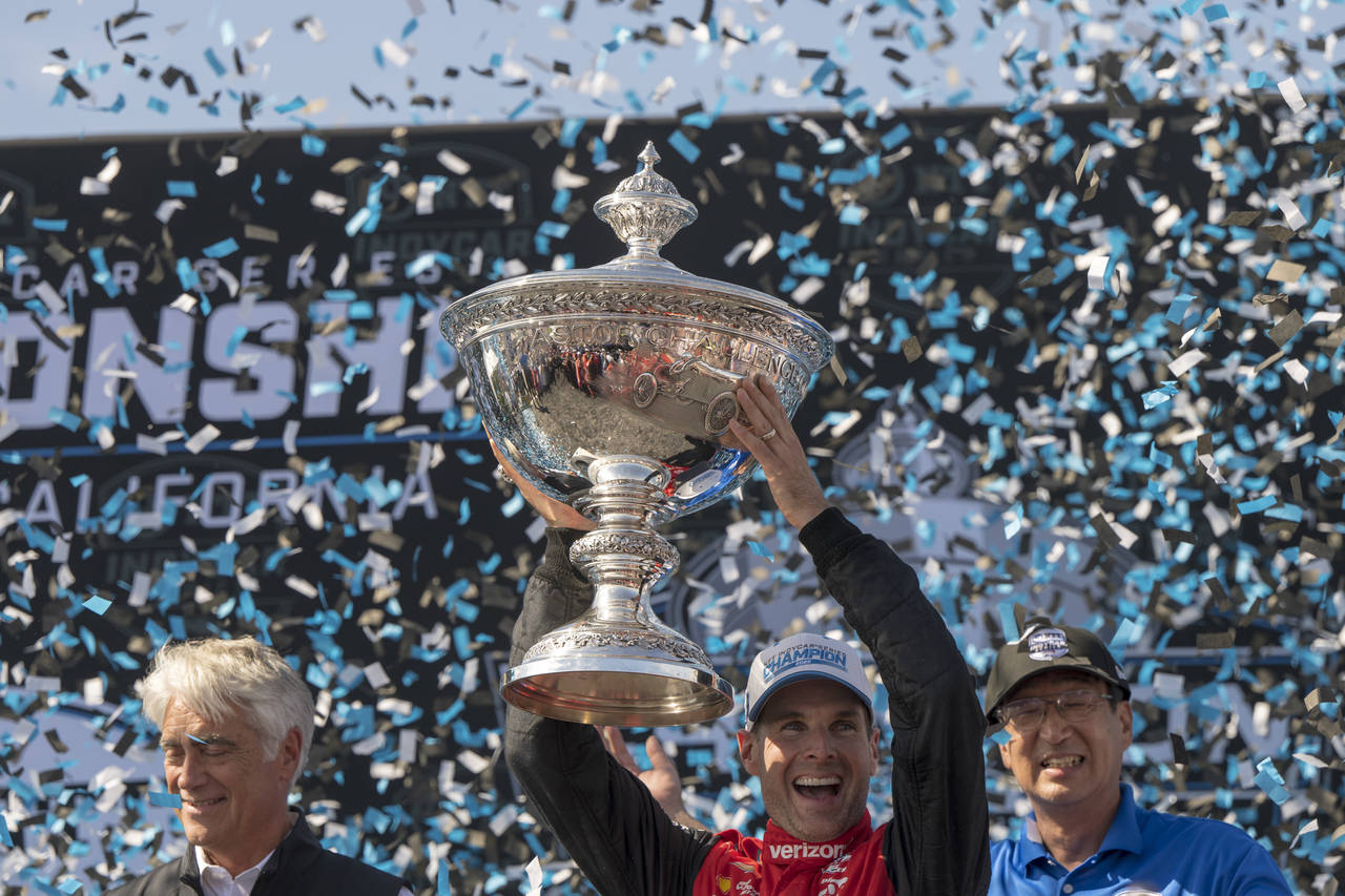Team Penske driver Will Power, of Australia, holds up the championship trophy after winning the cha...