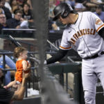 
              San Francisco Giants' Wilmer Flores, right, gives a young fan a greeting during the seventh inning of the team's baseball game against the Arizona Diamondbacks, Friday, Sept. 23, 2022, in Phoenix. (AP Photo/Rick Scuteri)
            