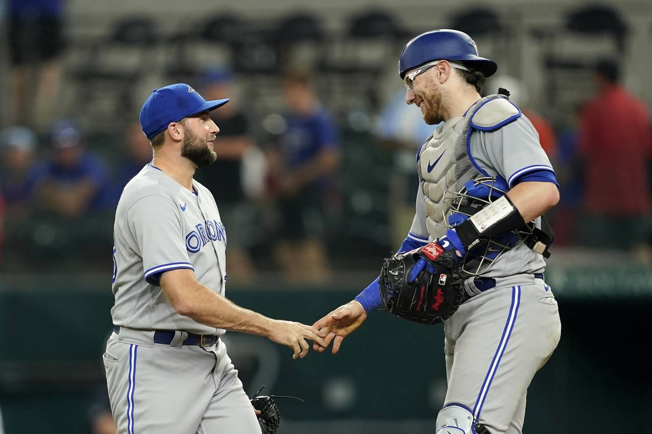 Toronto Blue Jays relief pitcher Tim Mayza, left, and catcher Danny Jansen, right, celebrate after ...