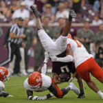
              Texas A&M wide receiver Ainias Smith (0) is flipped by Sam Houston State defensive back Darrel Hawkins-Williams, left, and linebacker Kavian Gaither (14) during the second half of an NCAA college football game Saturday, Sept. 3, 2022, in College Station, Texas. (AP Photo/David J. Phillip)
            