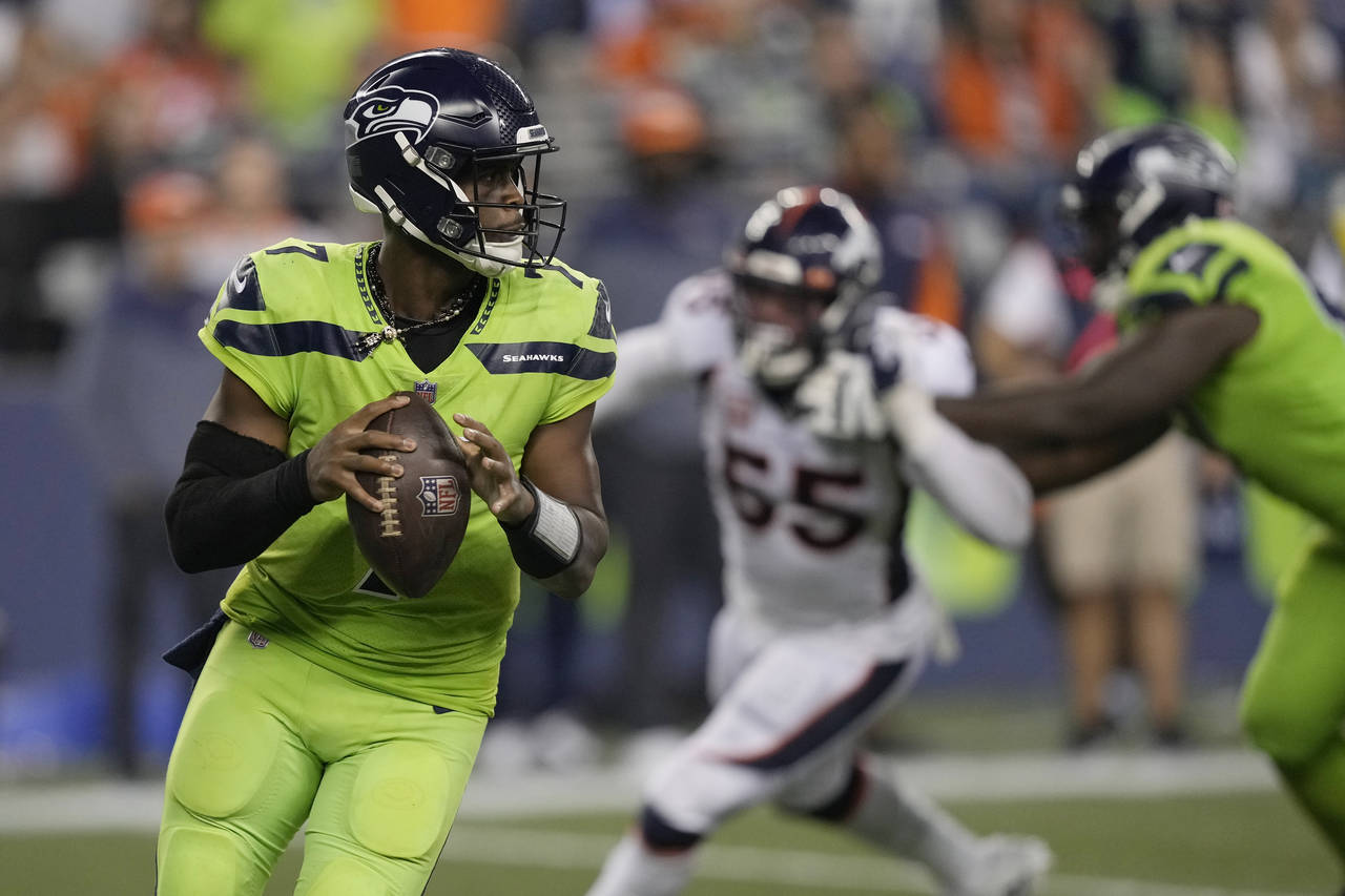 Seattle Seahawks quarterback Geno Smith, left, drops to pass against the Denver Broncos during the ...