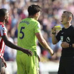 
              Refree Stuart Attwell show Manchester United's Harry Maguire a yellow card for a foul on Brentford's Ivan Toney during the English Premier League soccer match between Brentford and Manchester United at the Gtech Community Stadium in London, Saturday, Aug. 13, 2022. (AP Photo/Ian Walton)
            