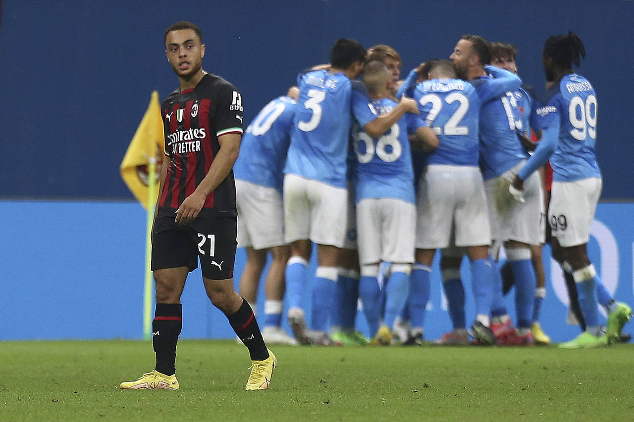 AC Milan's Sergiño Dest, left, walks away as Napoli players celebrate a goal during a Serie A socc...