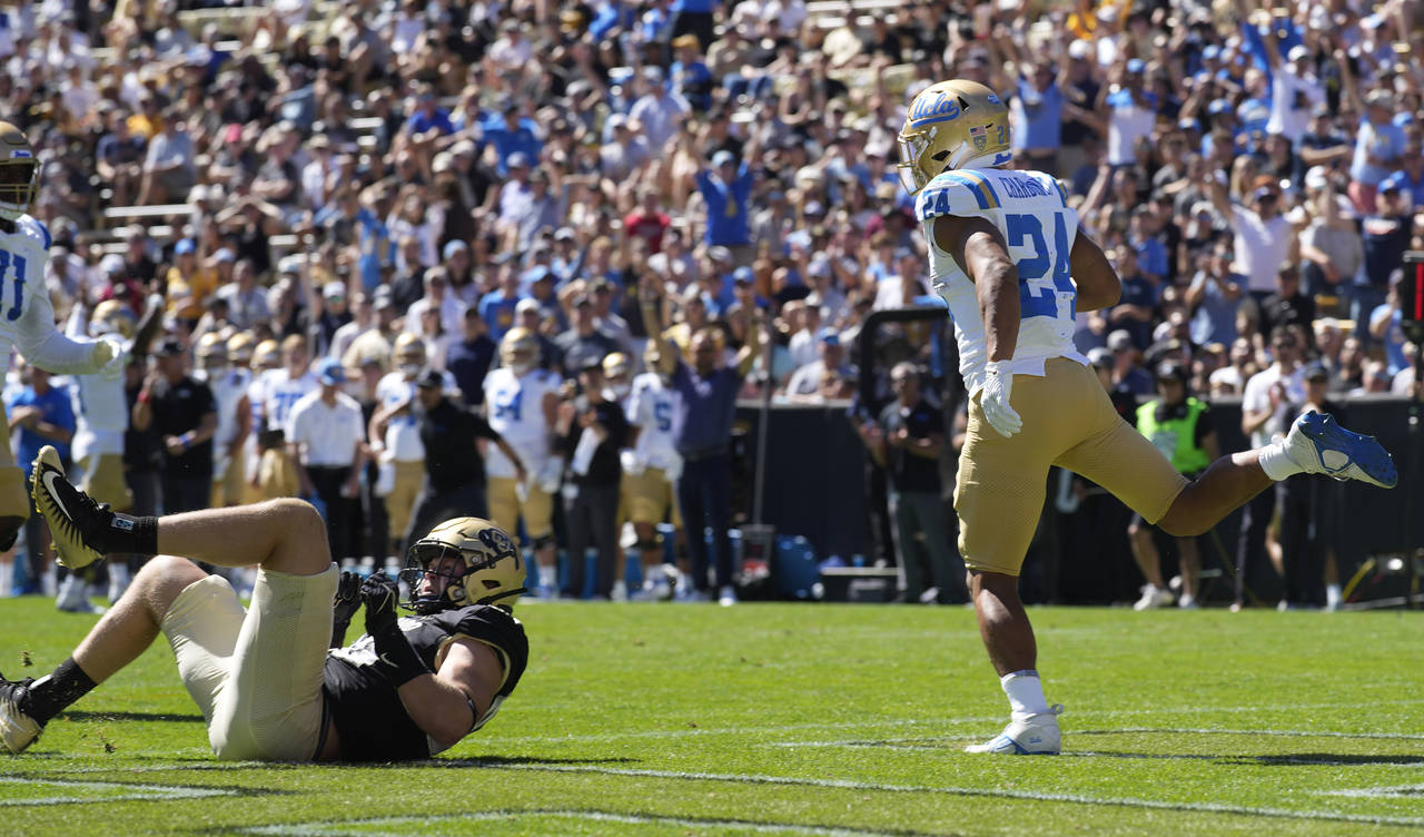 UCLA running back Zach Charbonnet, right, runs backwards into the end zone for a touchdown past Col...