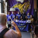 
              Cheerleders for the The Minnesota Vikings NFL team pose for pictures with supporters of the team at a fan interaction event at The Brotherhood Of Pursuits And Pastimes sports bar in Manchester, England, Wednesday, Sept. 28, 2022. A half-dozen NFL teams are aggressively targeting fans in Britain now that they have new marketing rights in the country. They’re signing commercial deals and hiring local media personalities in bids to expand their fanbases and tap international revenue. (AP Photo/Jon Super)
            