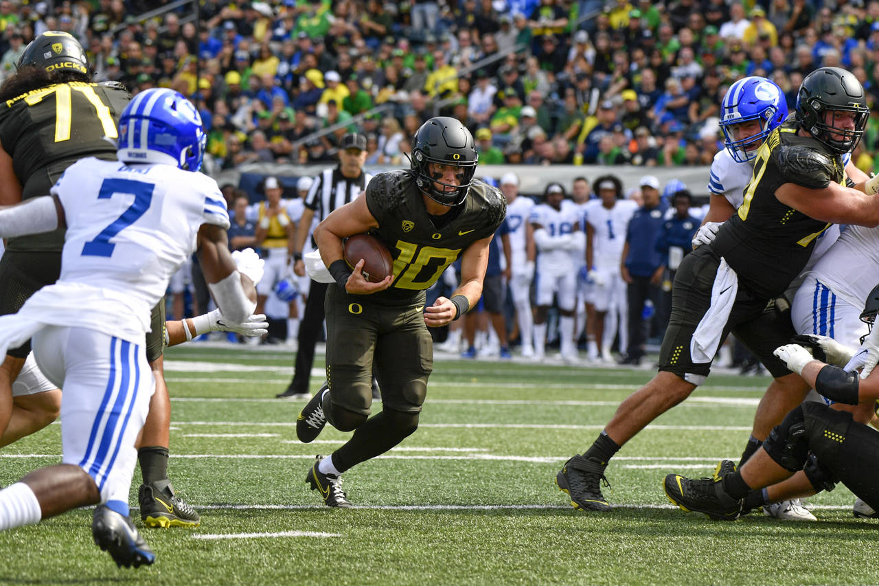Oregon quarterback Bo Nix runs through a hole in the BYU defense to score during the second half of...