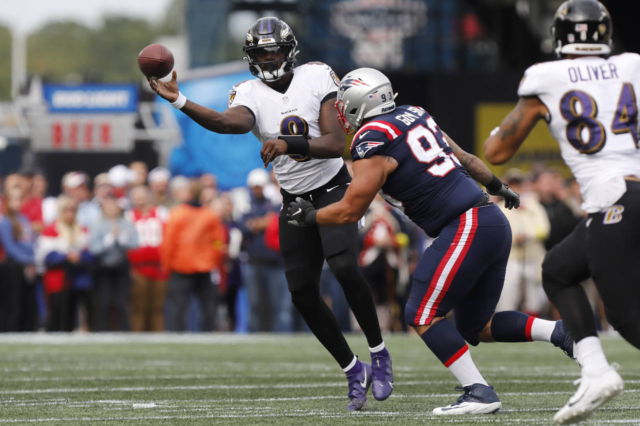 Baltimore Ravens quarterback Lamar Jackson (8) passes under pressure from New England Patriots defe...