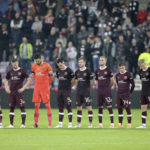 
              Hearts players stand wearing black armbands before the second half following the announcement of the death of Queen Elizabeth II, during the Europa Conference League Group A soccer match between Heart of Midlothian and Istanbul Basaksehir at Tynecastle Park, Edinburgh, Thursday, Sept. 8, 2022. (Robert Perry/PA via AP)
            