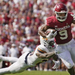 
              Oklahoma tight end Brayden Willis (9) avoids a tackle by UTEP defensive back Darius Baptist, left, and takes a Dillon Gabriel pass into the end zone for a touchdown in the first half of an NCAA college football game, Saturday, Sept. 3, 2022, in Norman, Okla. (AP Photo/Sue Ogrocki)
            