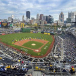 
              The city skyline is visible behind the center field wall as players, family and representatives of late players are seated on the outside edge of the infield at PNC Park near the number and banners of the Pittsburgh Pirates players that are part of the first team Hall of Fame class during a ceremony before a baseball game between the Pirates and the Toronto Blue Jays, Saturday, Sept. 3, 2022, in Pittsburgh. (AP Photo/Keith Srakocic)
            