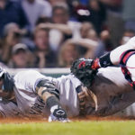 
              New York Yankees' Gleyber Torres smiles while sliding home safely on a throwing error by Boston Red Sox catcher Connor Wong, after driving in Aaron Judge and Aaron Hicks on a single, during the fifth inning of a baseball game at Fenway Park, Wednesday, Sept. 14, 2022, in Boston. (AP Photo/Charles Krupa)
            