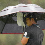 
              Byeong Hun An, of South Korea, takes cover from rain while waiting to putt on the sixth green of the Silverado Resort North Course during the final round of the Fortinet Championship PGA golf tournament in Napa, Calif., Sunday, Sept. 18, 2022. (AP Photo/Eric Risberg)
            
