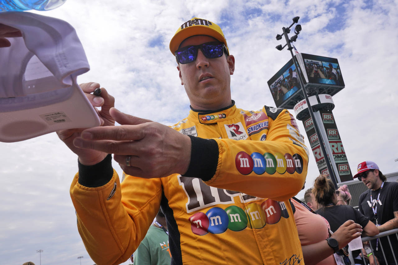 Kyle Busch gives an autograph during driver introductions prior to a NASCAR Cup Series auto race at...