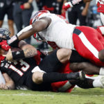 
              North Carolina State's Devin Leary (13) is sacked by Texas Tech's Tyree Wilson, bottom, and Bryce Ramirez during the first half of an NCAA college football game in Raleigh, N.C., Saturday, Sept. 17, 2022. (AP Photo/Karl B DeBlaker)
            