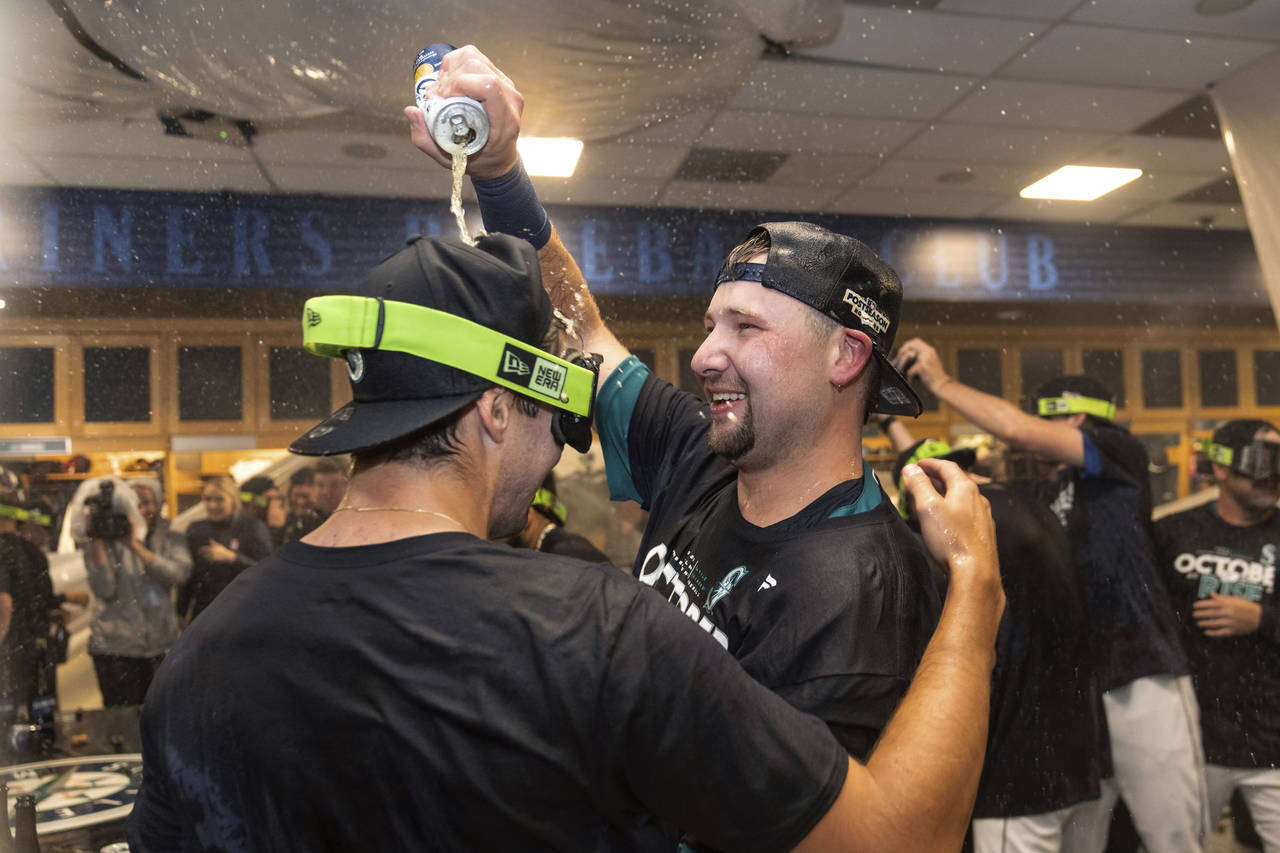 Seattle Mariners' Cal Raleigh, right, celebrates in the clubhouse after the team's baseball game ag...