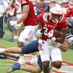
              North Carolina State's Delbert Mimms III (34) drags Charleston Southern's Quintin Seguin (3) into the end zone for a touchdown during the first half of an NCAA college football game in Raleigh, N.C., Saturday, Sept. 10, 2022. (AP Photo/Karl B DeBlaker)
            