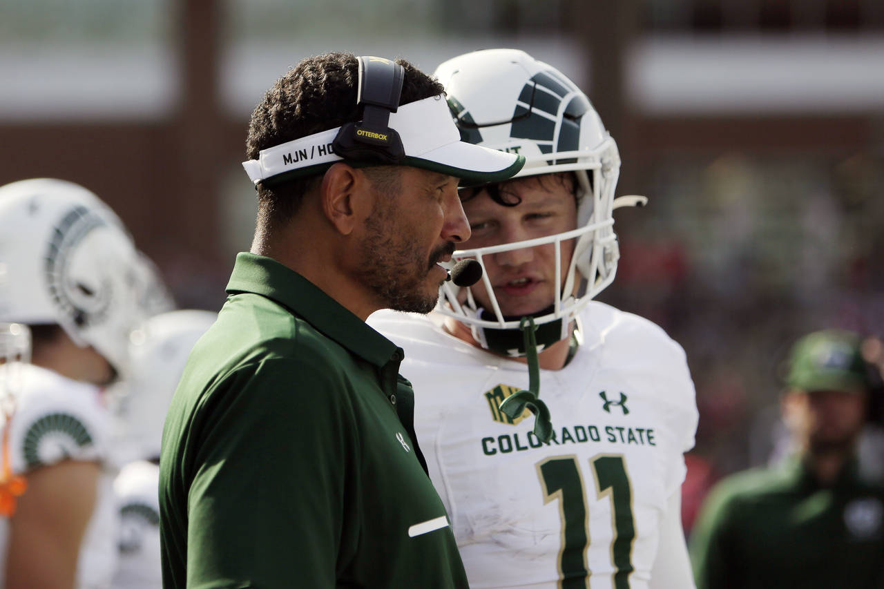 Colorado State head coach Jay Norvell, left, speaks with quarterback Clay Millen during the first h...