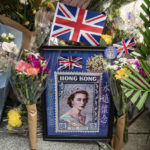 
              Flowers and a photograph are placed for Queen Elizabeth II outside the British Consulate in Hong Kong, Friday, Sept. 16, 2022. In Britain, Thousands of mourners waited for hours Thursday in a line that stretched for almost 5 miles (8 kilometers) across London for the chance to spend a few minutes filing past Queen Elizabeth II's coffin while she lies in state. (AP Photo/Anthony Kwan)
            