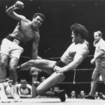 
              FILE - Japanese pro wrestler Antonio Inoki kicks the back of Muhammad Ali's leg during their boxing-wrestling bout at the Budokan hall in Tokyo, June 26, 1976. A popular Japanese professional wrestler and lawmaker Antonio Inoki, who faced a world boxing champion Muhammad Ali in a mixed martial arts match in 1979, has died at 79. The New Japan Pro-Wrestling Co. says Inoki, who was battling an illness, died earlier Saturday, Oct. 1, 2022. (AP Photo, File)
            
