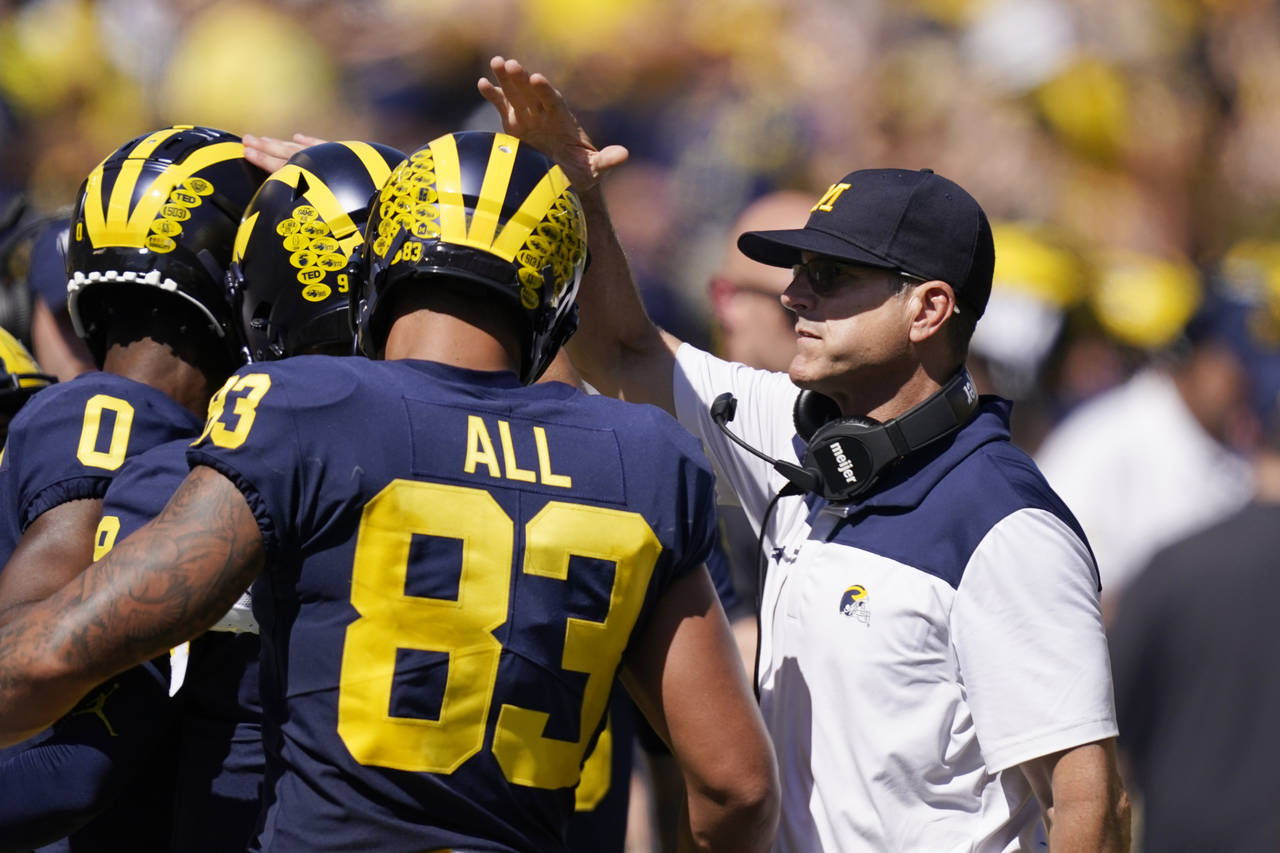 Michigan head coach Jim Harbaugh congratulates his players after a touchdown during the second half...