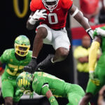 
              Georgia tight end Darnell Washington (0) hurdles Oregon defensive back Bryan Addison (13) after a catch in the first half of an NCAA college football game game Saturday, Sept. 3, 2022, in Atlanta. (AP Photo/John Bazemore)
            