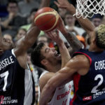 
              Spain's Willy Hernangomez, center, is challenged by Guerschon Yabusele, left, and Rudy Gobert of France, right, during the Eurobasket final basketball match between Spain and France in Berlin, Germany, Sunday, Sept. 18, 2022. (AP Photo/Michael Sohn)
            