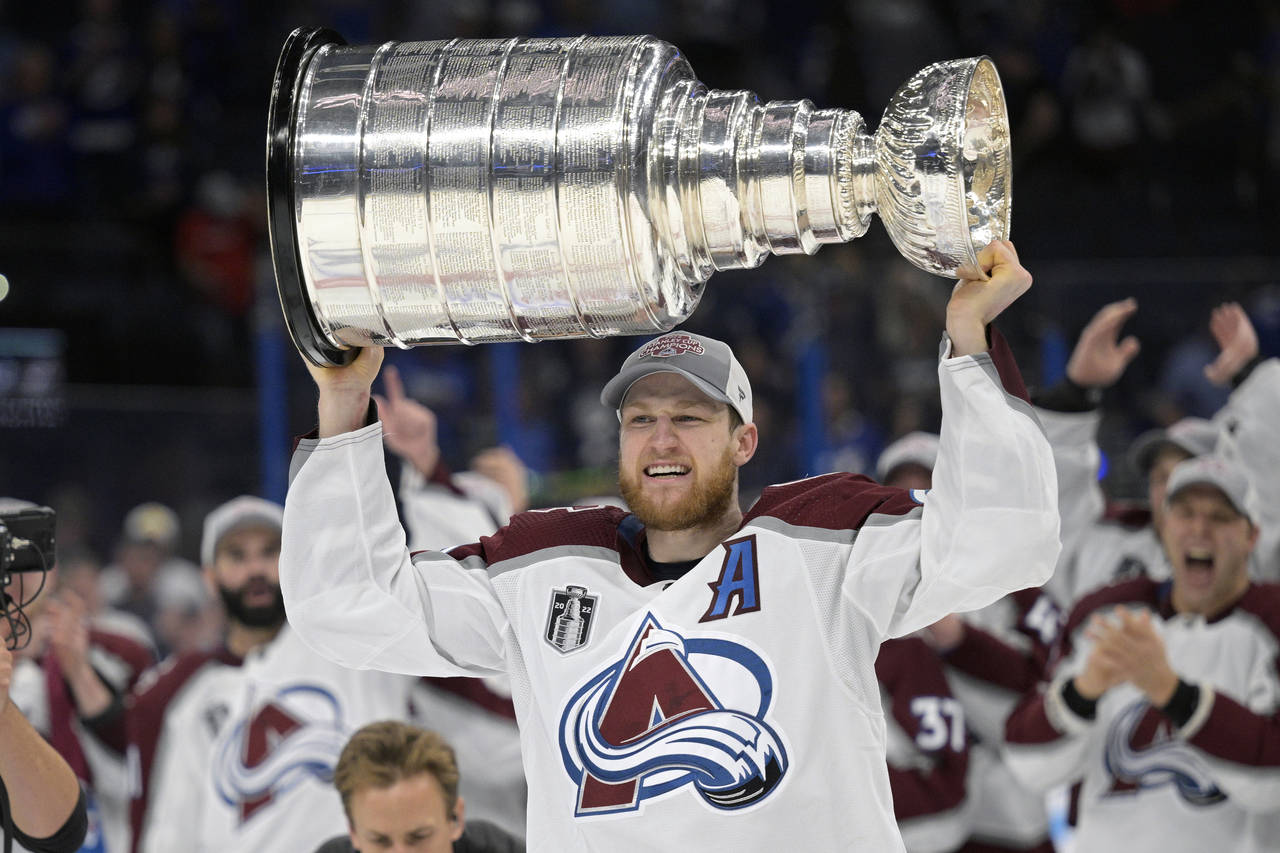 FILE - Colorado Avalanche center Nathan MacKinnon lifts the Stanley Cup after the team defeated the...