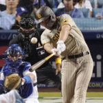 
              San Diego Padres' Brandon Drury, right, hits a two-run home run as Los Angeles Dodgers catcher Will Smith, left, and home plate umpire Alfonso Marquez watch during the third inning of a baseball game Friday, Sept. 2, 2022, in Los Angeles. (AP Photo/Mark J. Terrill)
            