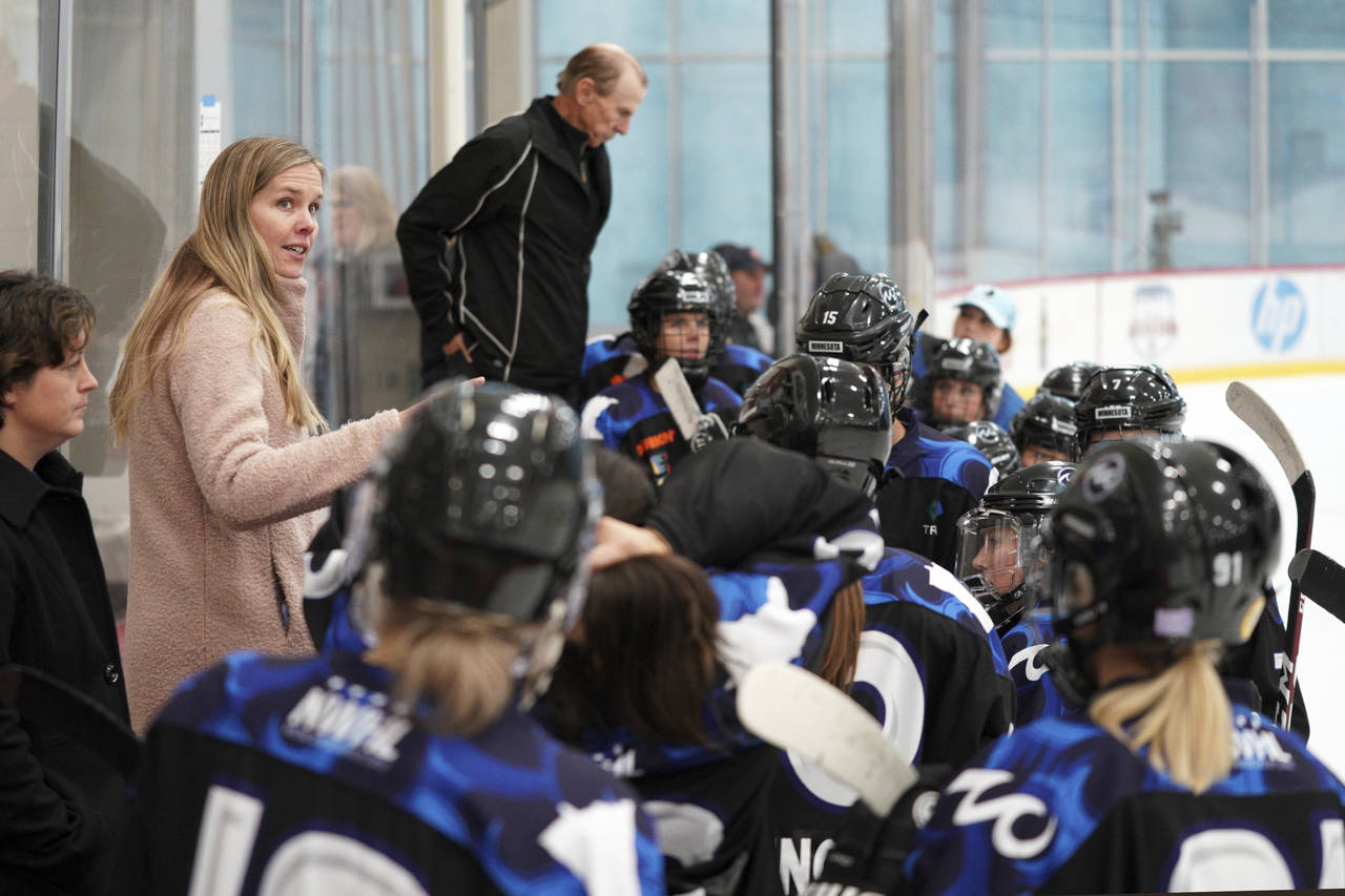 Minnesota Whitecaps coach Ronda Engelhardt talks with players on the bench during a hockey game aga...