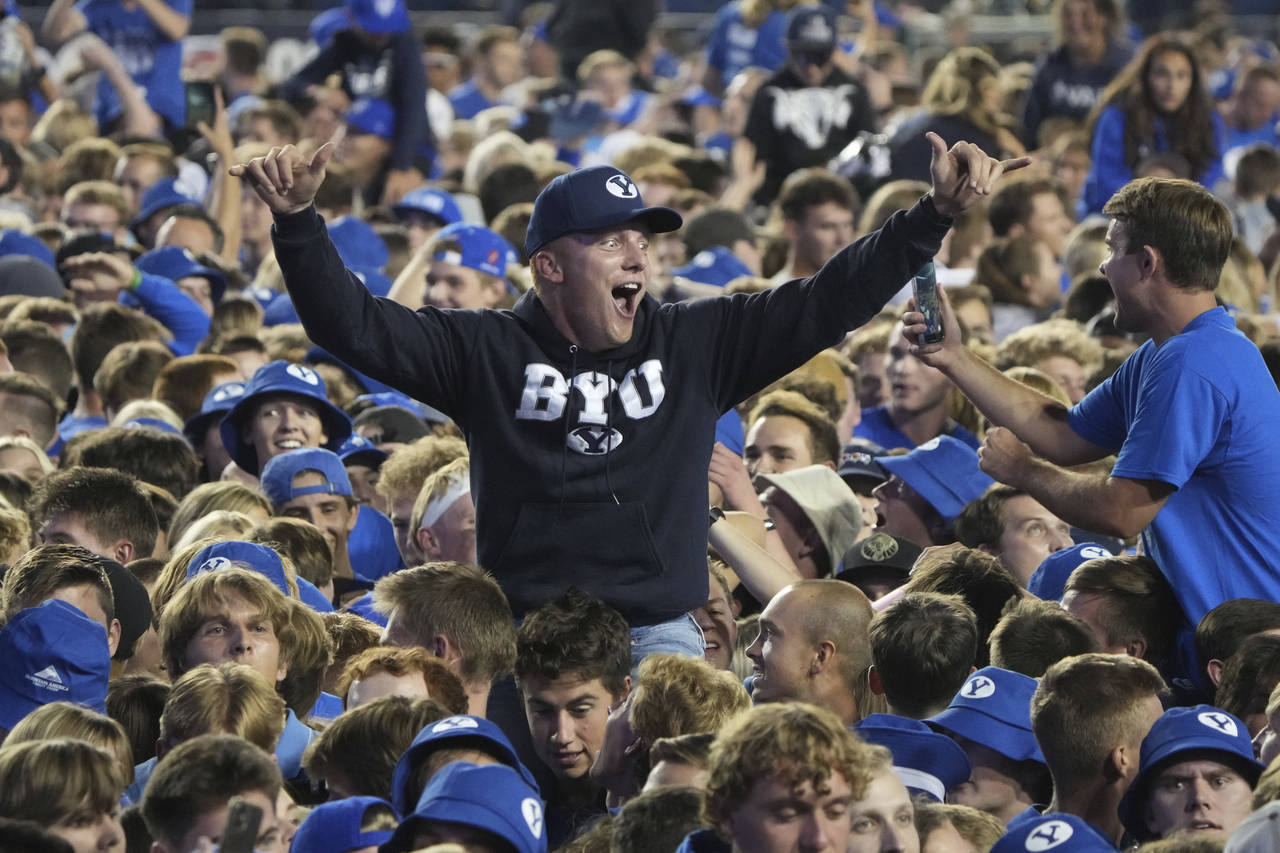 BYU fans storm the field and celebrate BYU's overtime win over Baylor after an NCAA college footbal...