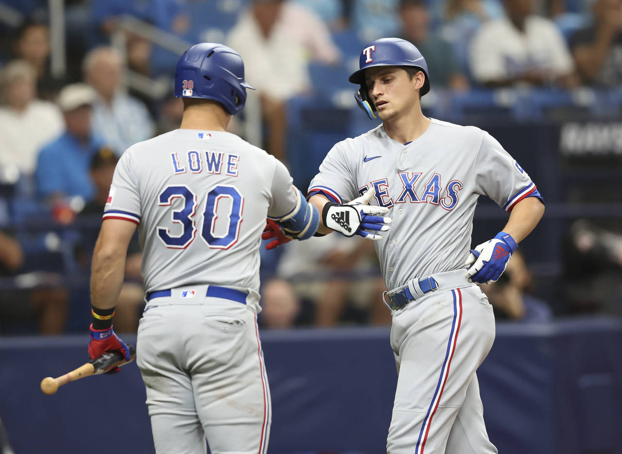 Texas Rangers' Corey Seager, right, celebrates with teammate Nathaniel Lowe (30) after hitting a ho...