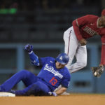 
              Los Angeles Dodgers' Max Muncy (13) reaches second on a double ahead of a throw to Arizona Diamondbacks shortstop Geraldo Perdomo, right, during the fourth inning of a baseball game against the Arizona Diamondbacks in Los Angeles, Thursday, Sept. 22, 2022. Will Smith scored. (AP Photo/Ashley Landis)
            