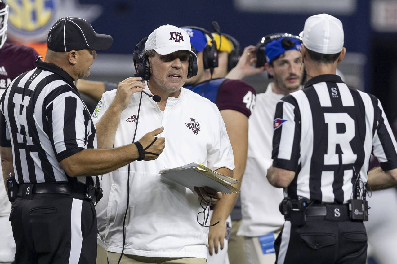 Texas A&M coach Jimbo Fisher confers with head line judge Chad Green, left, and referee Ken William...