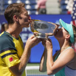 
              John Peers, left, and Storm Sanders, of Australia, kiss the championship trophy after winning the mixed doubles final against Kirsten Flipkens, of Belgium, and Edouard Roger-Vasselin, of France, at the U.S. Open tennis championships, Saturday, Sept. 10, 2022, in New York. (AP Photo/Matt Rourke)
            