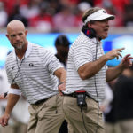
              Georgia head coach Kirby Smart, right, is pulled back to the sideline as he yells to his players on the field during the first half of an NCAA college football game against Samford, Saturday, Sept. 10, 2022 in Athens, Ga. (AP Photo/John Bazemore)
            