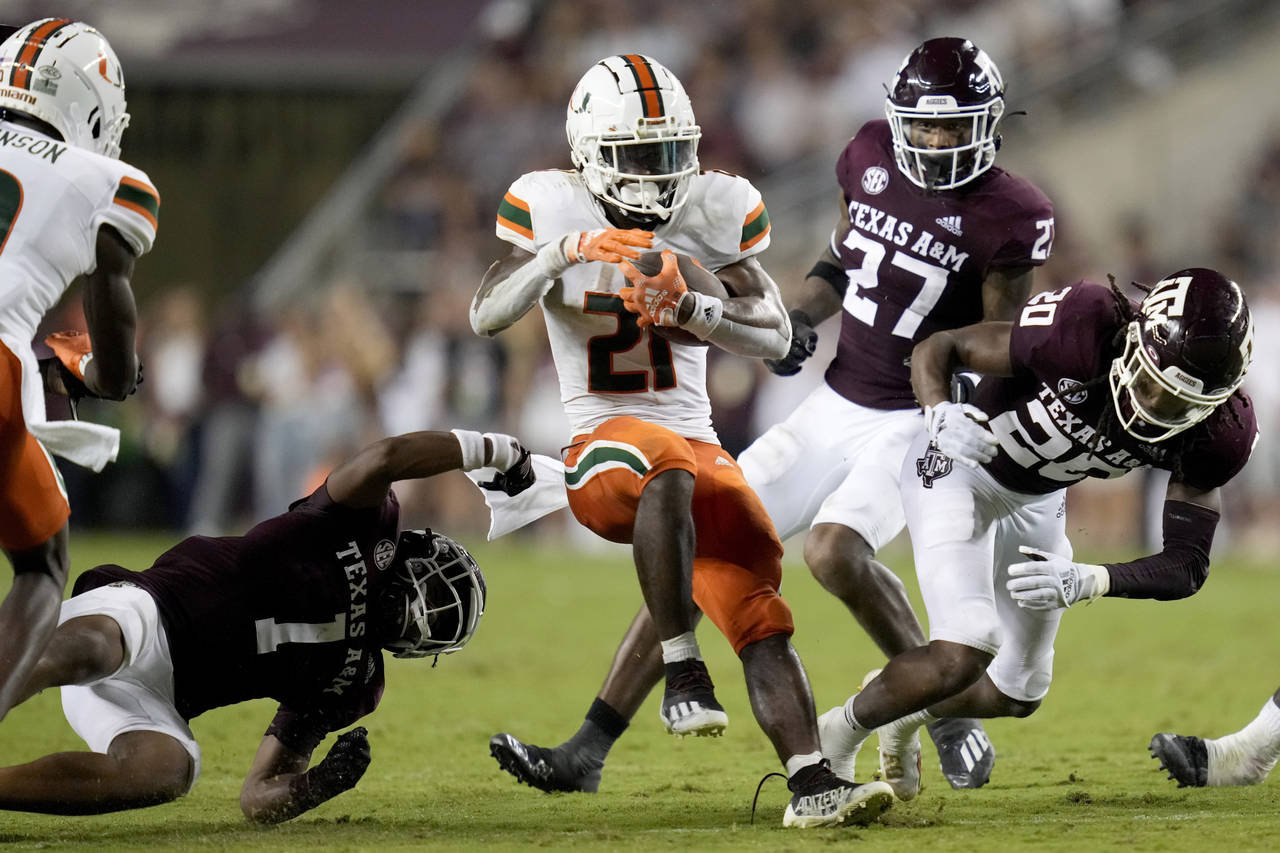 Miami running back Henry Parrish Jr. (21) spins out of a tackle attempt between Texas A&M's Bryce A...